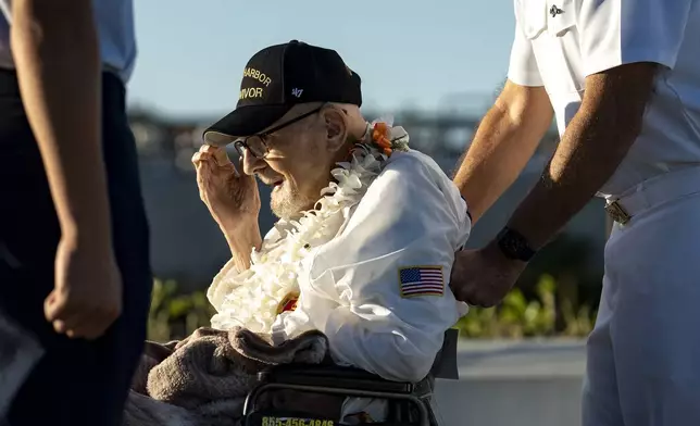 Pearl Harbor survivor Ira "Ike" Schab, 104, from Beaverton, Ore., center, salutes as he leaves the stand during the 83rd Pearl Harbor Remembrance Day ceremony, Saturday, Dec. 7, 2024, in Honolulu. (AP Photo/Mengshin Lin)