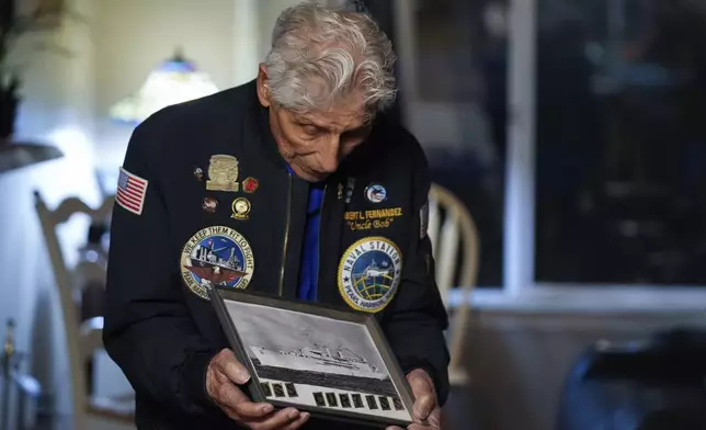 Navy veteran Bob Fernandez hods a photograph of the USS Curtiss, in which he served during the Pearl Harbor attack, Tuesday, Nov. 19, 2024, in Lodi, Calif. (AP Photo/Godofredo A. Vásquez)