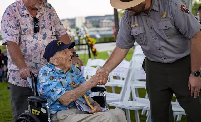 Ken Stevens, 102, of Powers, Ore., who survived the attack on Pearl Harbor shakes hand with a park ranger before the 83rd Pearl Harbor Remembrance Day ceremony, Saturday, Dec. 7, 2024, in Honolulu. (AP Photo/Mengshin Lin)