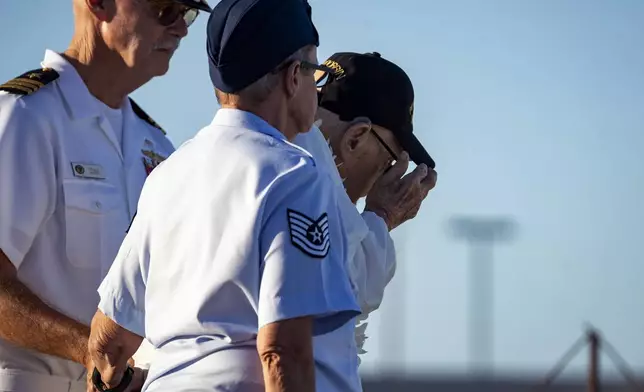 Pearl Harbor survivor Ira "Ike" Schab, 104, from Beaverton, Ore., center, stand by his son, retired Navy Cmdr. Karl Schab, and daughter, retired Air Force veteran to salute behalf of all the Pearl Harbor survivors during the 83rd Pearl Harbor Remembrance Day ceremony, Saturday, Dec. 7, 2024, in Honolulu. (AP Photo/Mengshin Lin)