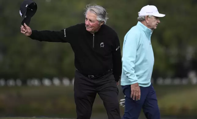 Gary Player, left, acknowledges the crowd as he and Nick Price, right, walk to the 18th green during the final round of the PNC Championship golf tournament, Sunday, Dec. 22, 2024, in Orlando, Fla. (AP Photo/Phelan M. Ebenhack)