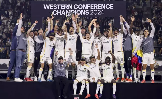 Los Angeles Galaxy players celebrate on the podium after a win over the Seattle Sounders in an MLS Western Conference final soccer match, Saturday, Nov. 30, 2024, in Carson, Calif. (AP Photo/Etienne Laurent)