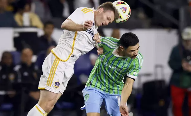 Los Angeles Galaxy defender John Nelson, left, heads the ball over Seattle Sounders midfielder Alex Roldan during the first half an MLS Western Conference final soccer match, Saturday, Nov. 30, 2024, in Carson, Calif. (AP Photo/Etienne Laurent)