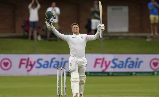 South Africa's Ryan Rickelton raises his bat and helmet after reaching his maiden Test match century during the first day of the second Test cricket match between South Africa and Sri Lanka, at St George's Park in Gqeberha, South Africa, Thursday, Dec. 5, 2024. (AP Photo/Themba Hadebe)