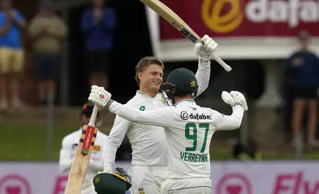 South Africa's Ryan Rickelton, left, celebrates with teammate Kyle Verreynne, after reaching his maiden Test match century during the first day of the second Test cricket match between South Africa and Sri Lanka, at St George's Park in Gqeberha, South Africa, Thursday, Dec. 5, 2024. (AP Photo/Themba Hadebe)