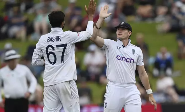 England bowler Shoaib Bashir, left, is congratulated by teammate Matthew Potts after taking the wicket of New Zealand's Glenn Phillips during play on day three of the third cricket test between England and New Zealand in Hamilton, New Zealand, Monday, Dec. 16, 2024. (Andrew Cornaga/Photosport via AP)