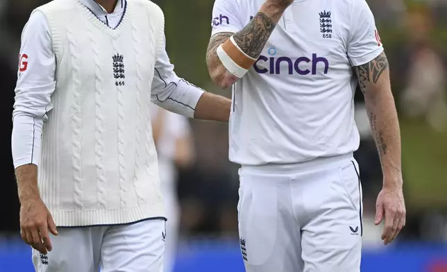 England captain Ben Stokes, right, is consoled by teammate Joe Root as he leaves the field with an injury during play on day three of the third cricket test between England and New Zealand in Hamilton, New Zealand, Monday, Dec. 16, 2024. (Andrew Cornaga/Photosport via AP)