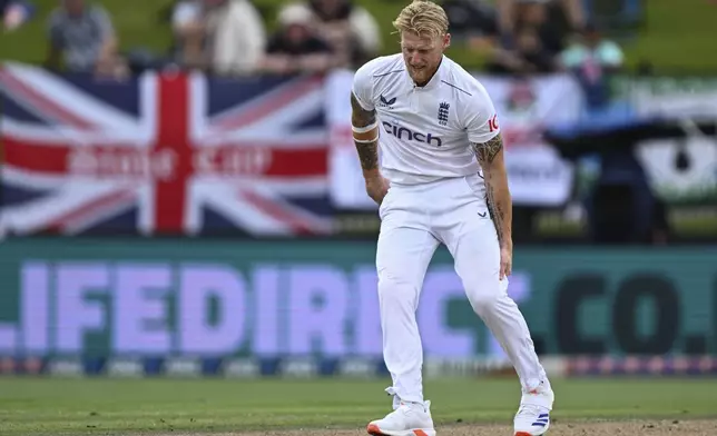 England captain Ben Stokes grabs at his leg while bowling during play on day three of the third cricket test between England and New Zealand in Hamilton, New Zealand, Monday, Dec. 16, 2024. (Andrew Cornaga/Photosport via AP)