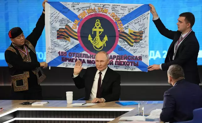 Men hold a replica of the banner of the 155th Marine Brigade of the Pacific Fleet, participating in a special military operation in Ukraine during Russian President Vladimir Putin's annual news conference and call-in show at Gostinny Dvor in Moscow, Russia, Thursday, Dec. 19, 2024. (AP Photo/Alexander Zemlianichenko)