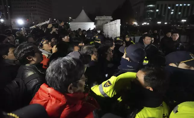 People try to enter as police officers stand guard in front of the National Assembly in Seoul, South Korea, Tuesday, Dec. 3, 2024. (AP Photo/Lee Jin-man)