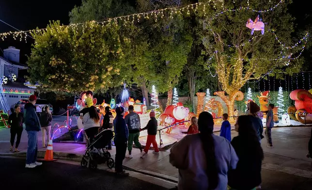 Local residents walk through the Wakefield Winter Wonderland neighborhood decorated with Christmas lights in Santa Clarita, Calif. on Dec. 17, 2024. (AP Photo/Richard Vogel)