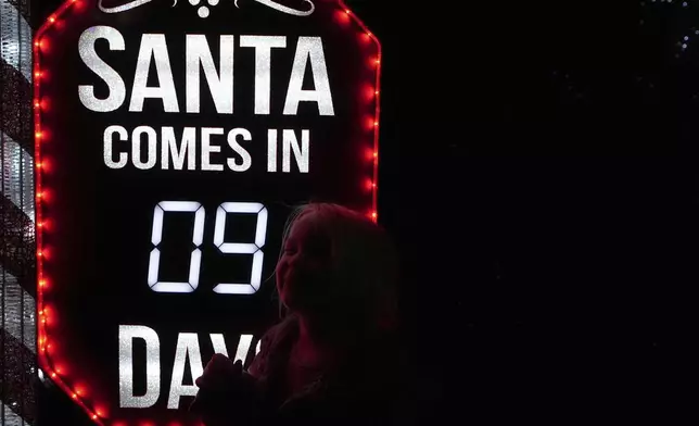 A child shows excitement at a sign that says "Santa Comes in Nine Days" at the Lights of Joy display Monday, Dec. 16, 2024, in Kennesaw, Ga. (AP Photo/Brynn Anderson)