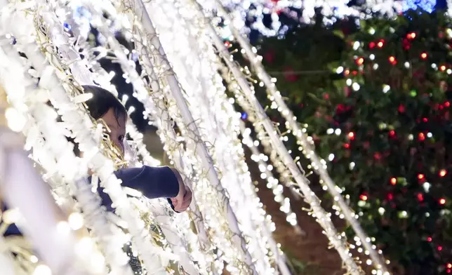 A child pokes their head through a light display at the Lights of Joy display Monday, Dec. 16, 2024, in Kennesaw, Ga. (AP Photo/Brynn Anderson)