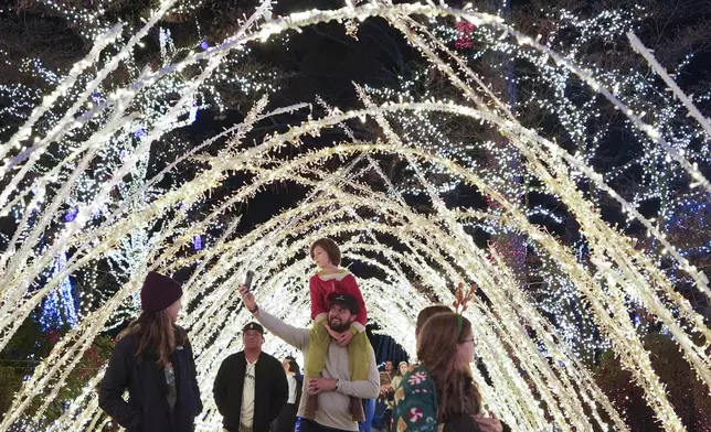 A family walks through a light display at the Lights of Joy display Monday, Dec. 16, 2024, in Kennesaw, Ga. (AP Photo/Brynn Anderson)