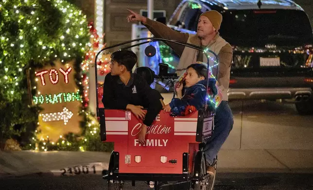 Children are wheeled through the Wakefield Winter Wonderland lighted neighborhood to view the Christmas lights in Santa Clarita, Calif. on Dec. 17, 2024. (AP Photo/Richard Vogel)