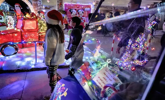 Local children walk the Wakefield Winter Wonderland neighborhood decorated with Christmas lights in Santa Clarita, Calif. on Dec. 17, 2024. (AP Photo/Richard Vogel)