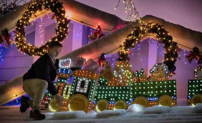 Resident Bryan Cobb puts the finishing touches on the lights on his house for the Wakefield Winter Wonderland lighted street in Santa Clarita, Calif. on Dec. 17, 2024. (AP Photo/Richard Vogel)