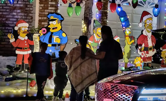 The Simpsons cartoon characters decorate the front of a Wakefield Winter Wonderland as local residents walk the neighborhood decorated with Christmas lights in Santa Clarita, Calif. on Dec. 17, 2024. (AP Photo/Richard Vogel)