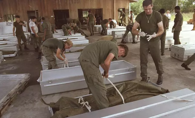 FILE - U.S. military personnel place bodies in coffins at the airport in Georgetown, Guyana, after collecting the bodies of more than 900 members of the People's Temple who committed suicide in Jonestown, Guyana on Nov. 18, 1978. (AP Photo, File)