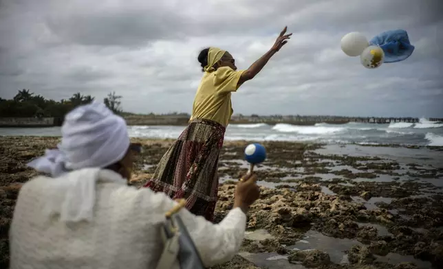 Gloria Esperanza Reyes makes her monthly offering of flowers and sugarcane syrup to Yemaya, the Yoruba goddess of the sea, in Havana, Cuba, Wednesday, Feb. 14, 2024. She also is venerated as Our Lady of Regla, a Black Madonna at a Catholic church across the Bay of Havana. (AP Photo/Ramon Espinosa)