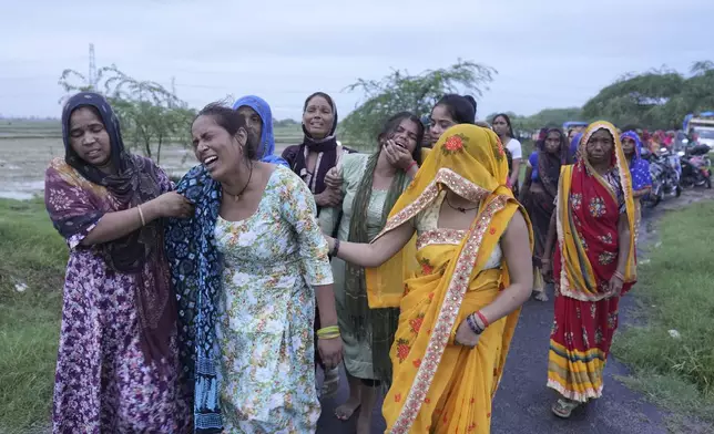 Bharti Kumari, second left, and Sonam, centre in green, weep as the body of their mother, Savitri Devi, 50, who died from a stampede at a religious festival, is carried for cremation in Ramnagar, in the northern Indian state of Uttar Pradesh, Wednesday, July 3, 2024. (AP Photo/Rajesh Kumar Singh)