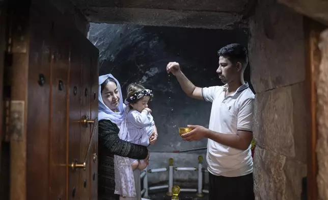 A child is baptized in Lalish, the Yazidi's most holy temple, in the Shekhan district of the Kurdistan region of Iraq, Monday, June 24, 2024. (AP Photo/Julia Zimmermann)