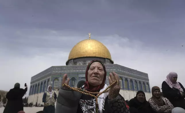 A Muslim woman prays near the Dome of the Rock Mosque at the Al-Aqsa Mosque compound for the third Friday prayers of the holy month of Ramadan in the Old City of Jerusalem, Friday, March 29, 2024. (AP Photo/Mahmoud Illean)