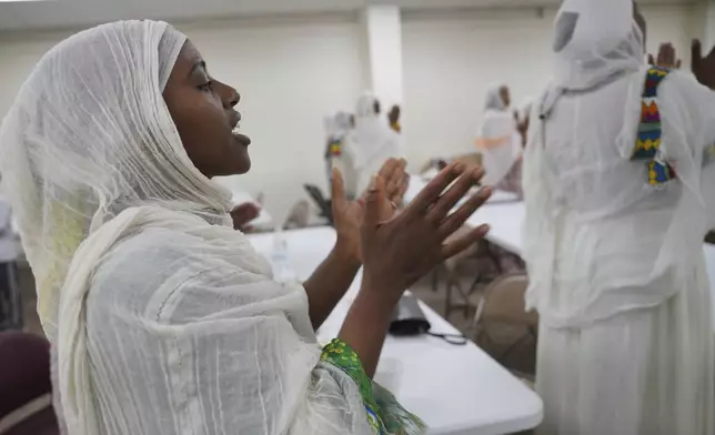 Mintamir Endanew, left, and other members of the Ethiopian Orthodox Tewahedo Church pray after a post-liturgy lunch of pancake-like injera bread on Sunday, Oct. 20, 2024, in Worthington, Minn. (AP Photo/Jessie Wardarski)