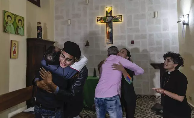 Rev. Yileyvis Cruz stands by as congregants embrace during a service at the Metropolitan Community Church, an LGBTQ+ inclusive house of worship, in Matanzas, Cuba, Friday, Feb. 2, 2024. In recent years, the communist-run island barred anti-gay discrimination, and a 2022 government-backed "family law" allowed same-sex couples the right to marry and adopt. (AP Photo/Ramon Espinosa)