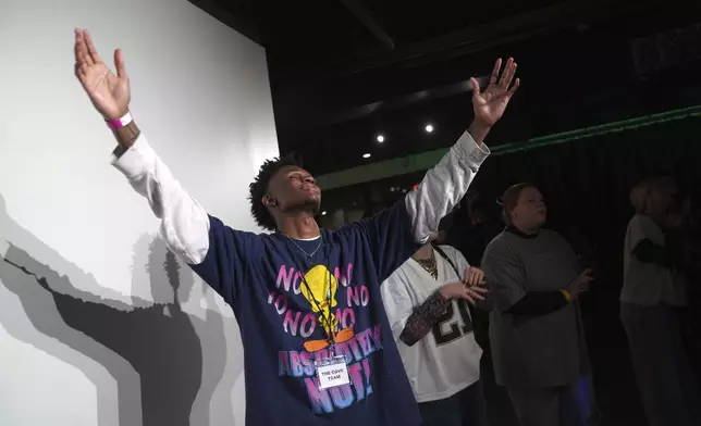 Jeremiah Manley, left, and other attendees at The Cove, an 18-and-up, pop-up Christian nightclub, raise their arms in worship on Saturday, Feb. 17, 2024, in Nashville, Tenn. The Cove was started last year by seven Black Christian men in their 20s who sought to build a thriving community and a welcoming space for young adults outside houses of worship. (AP Photo/Jessie Wardarski)