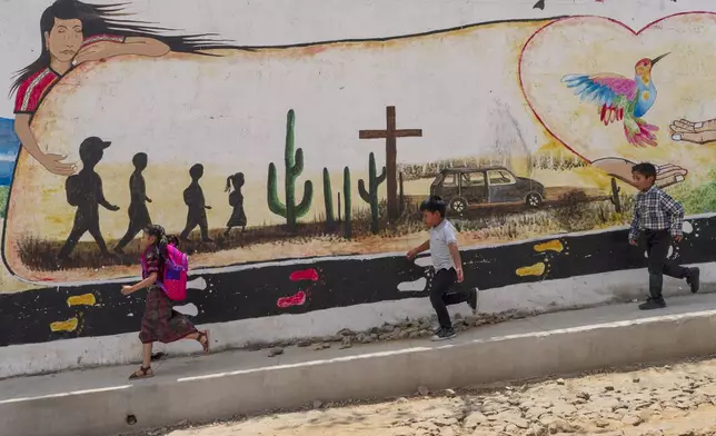 Children run past a mural memorializing 19 locals who were shot and burned in Camargo, Mexico, as they attempted to migrate to the U.S., in Comitancillo, Guatemala, Tuesday, March 19, 2024. In this small town, nearly two dozen local migrants have died in recent mass tragedies: either asphyxiated in the trailer in San Antonio, Texas, in June 2022 or shot and set afire by rogue police officers in Camargo, Mexico, in January 2021. (AP Photo/Moises Castillo)