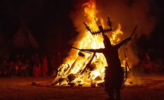 An Apache Crown Dancer whirls around the bonfire during a coming-of-age blessing ceremony for two young tribe women in Mescalero, New Mexico, Saturday, July 13, 2024. (AP Photo/Andres Leighton)