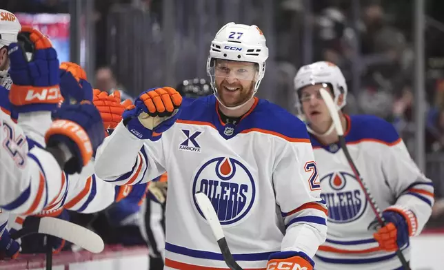 Edmonton Oilers defenseman Brett Kulak is congratulated as he passes the team box after scoring a goal in the third period of an NHL hockey game against the Colorado Avalanche Saturday, Nov. 30, 2024, in Denver. (AP Photo/David Zalubowski)