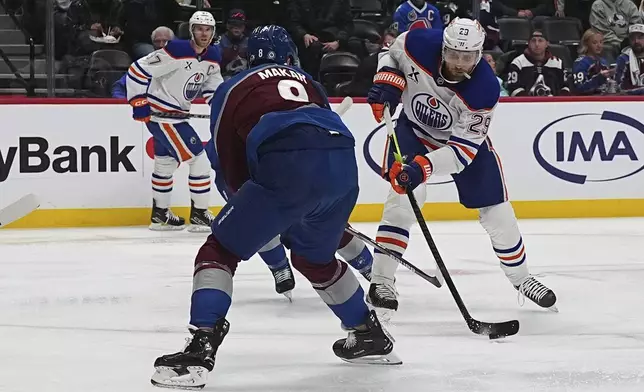 Edmonton Oilers center Leon Draisaitl, right, shoots the puck as Colorado Avalanche defenseman Cale Makar (8) covers in the second period of an NHL hockey game Saturday, Nov. 30, 2024, in Denver. (AP Photo/David Zalubowski)