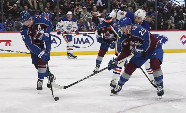 Colorado Avalanche defenseman Cale Makar, left, clears the puck while Edmonton Oilers center Leon Draisaitl, back right, and Avalanche right wing Logan O'Connor (25) look on in the second period of an NHL hockey game Saturday, Nov. 30, 2024, in Denver. (AP Photo/David Zalubowski)