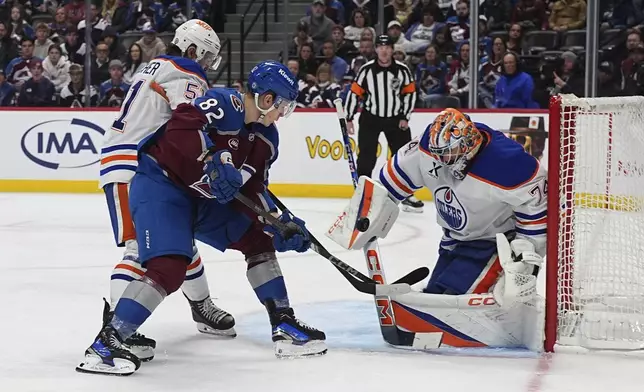 Colorado Avalanche center Ivan Ivan, front left, drives past Edmonton Oilers defenseman Troy Stecher, back left, to put a shot on goaltender Stuart Skinner in the third period of an NHL hockey game Saturday, Nov. 30, 2024, in Denver. (AP Photo/David Zalubowski)