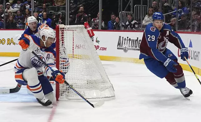 Colorado Avalanche center Nathan MacKinnon, right, wraps around the net as Edmonton Oilers defenseman Darnell Nurse covers in the third period of an NHL hockey game Saturday, Nov. 30, 2024, in Denver. (AP Photo/David Zalubowski)