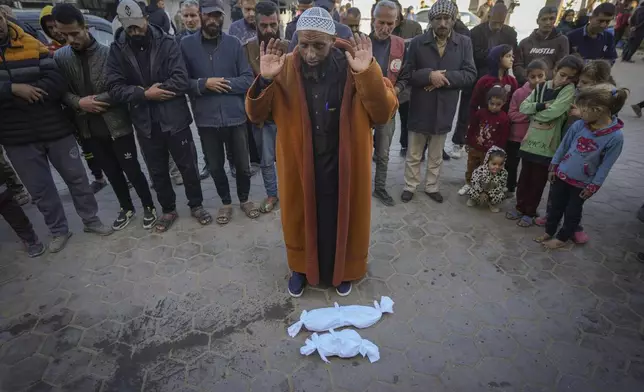 Imam Islam Abu Suaied prays over the bodies of two babies before their burial at the Al-Aqsa Martyrs Hospital in Deir al-Balah, central Gaza Strip, Sunday, Dec. 29, 2024. One baby died at birth, while the other, 20-day-old Jomaa al-Batran, succumbed to hypothermia. According to local health officials, at least three other babies in Gaza have died from the cold in recent weeks.(AP Photo/Abdel Kareem Hana)