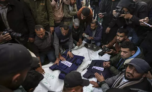 Palestinians, mostly journalists, gather around the bodies of five Palestinian journalists who were killed by an Israeli airstrike in Gaza City, at the Al-Aqsa Hospital in Deir al-Balah, Thursday, Dec. 26, 2024. (AP Photo/Abdel Kareem Hana)