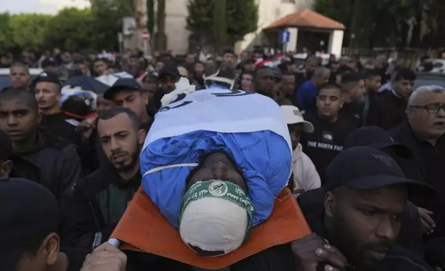 Mourners carry the bodies of killed Palestinians, some wrapped with the Islamic Jihad flag, during their funeral following the withdrawal of the Israeli army, in the West Bank city of Tulkarem, Thursday, Dec. 26, 2024. (AP Photo/Nasser Nasser)