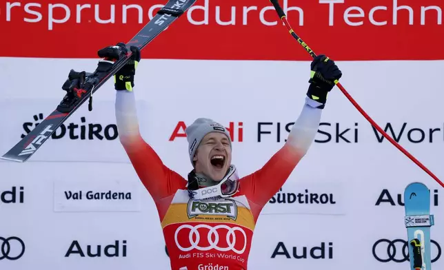 Switzerland's Marco Odermatt celebrates on the podium after winning an alpine ski, men's World Cup downhill, in Val Gardena, Italy, Saturday, Dec. 21, 2024. (AP Photo/Alessandro Trovati)