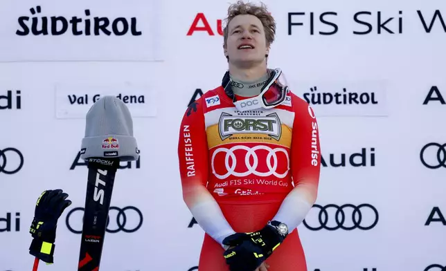 Switzerland's Marco Odermatt listens to the national anthem on the podium after winning an alpine ski, men's World Cup downhill, in Val Gardena, Italy, Saturday, Dec. 21, 2024. (AP Photo/Alessandro Trovati)