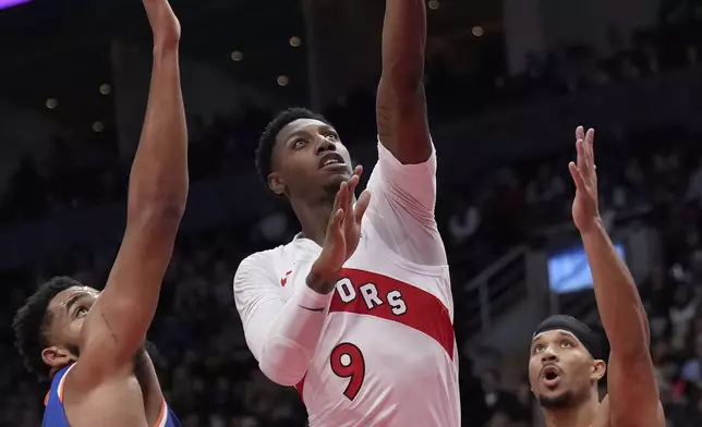 Toronto Raptors guard RJ Barrett (9) drives to the net between New York Knicks center Karl-Anthony Towns and teammate Josh Hart (3) during the first half of an NBA basketball game in Toronto, Monday, Dec. 9, 2024. (Nathan Denette/The Canadian Press via AP)