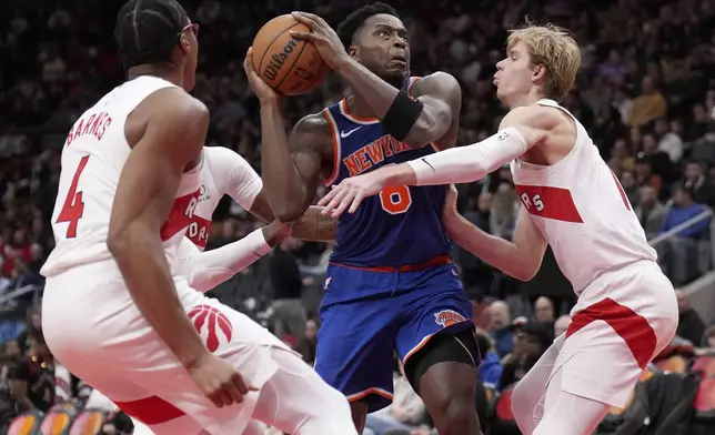 New York Knicks forward OG Anunoby drives past Toronto Raptors forward Scottie Barnes (4) and teammate Gradey Dick during the second half of an NBA basketball game in Toronto, Monday, Dec. 9, 2024. (Nathan Denette/The Canadian Press via AP)