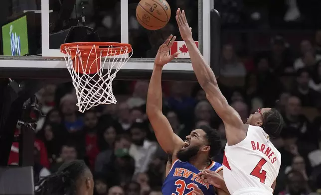 Toronto Raptors forward Scottie Barnes (4) fouls New York Knicks center Karl-Anthony Towns (32) during the first half of an NBA basketball game in Toronto, Monday, Dec. 9, 2024. (Nathan Denette//The Canadian Press via AP)