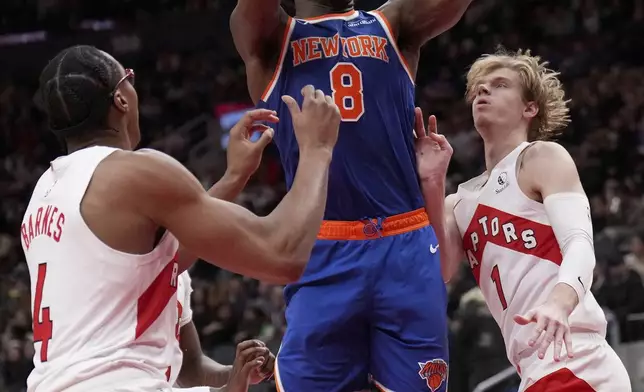 New York Knicks forward OG Anunoby (8) drives past Toronto Raptors forward Scottie Barnes (4) and teammate Gradey Dick (1) during the second half of an NBA basketball game in Toronto, Monday, Dec. 9, 2024. (Nathan Denette/The Canadian Press via AP)