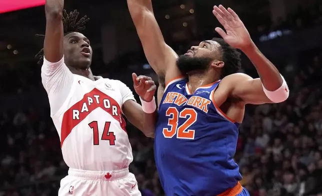 Toronto Raptors guard Ja'Kobe Walter (14) shoots over New York Knicks center Karl-Anthony Towns (32) during the first half of an NBA basketball game in Toronto, Monday, Dec. 9, 2024. (Nathan Denette/The Canadian Press via AP)