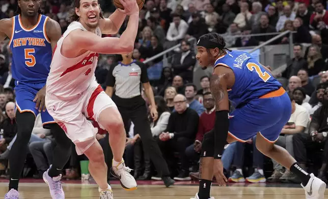 Toronto Raptors forward Kelly Olynyk (41) drives past New York Knicks forward Precious Achiuwa (5) and teammate Miles McBride (2) during the first half of an NBA basketball game in Toronto, Monday, Dec. 9, 2024. (Nathan Denette//The Canadian Press via AP)