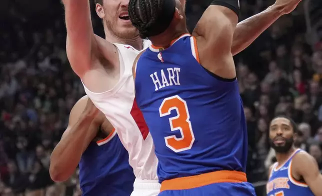 Toronto Raptors center Jakob Poeltl (19) drives to the net as New York Knicks guard Josh Hart (3) defends during the first half of an NBA basketball game in Toronto, Monday, Dec. 9, 2024. (Nathan Denette//The Canadian Press via AP)