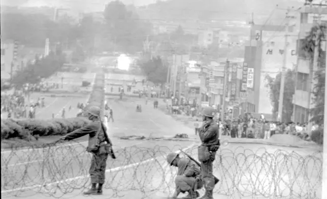 FILE- Government soldiers are erecting a roadblock on a street leading to downtown Gwangju (Kwangju), with citizens looking on, May 26, 1980. Rebels are holding the provincial capital in south western Korea days now. (AP Photo/ File)